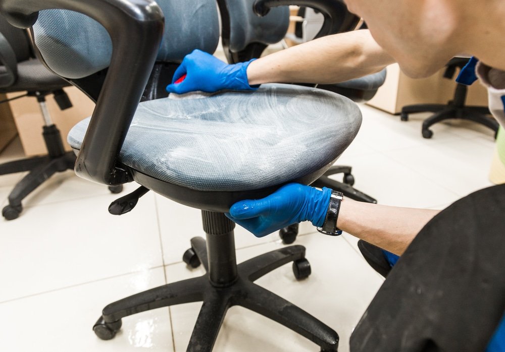 A man wearing gloves cleaning a mesh seat