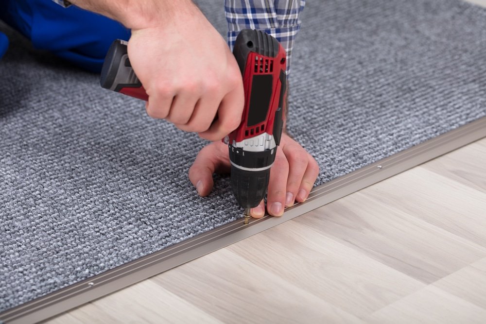Close up of a hand driving the screw into the subfloor