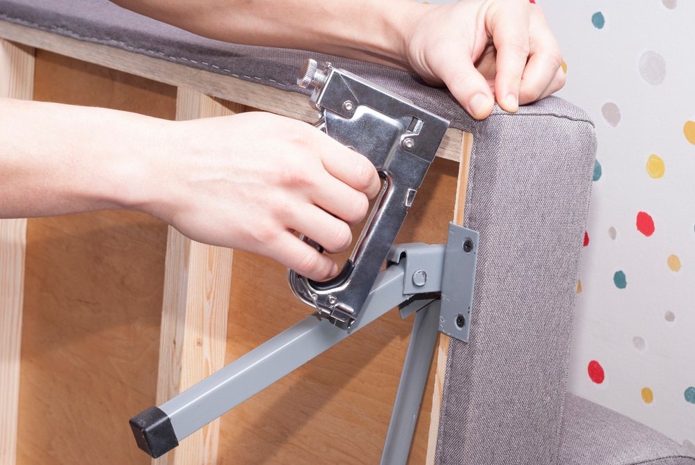 Close up of hands stapling a new fabric in a furniture