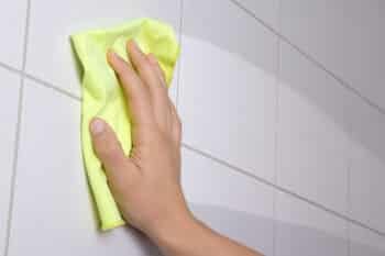 Hand with yellow rag cleaning the ceramic tiles
