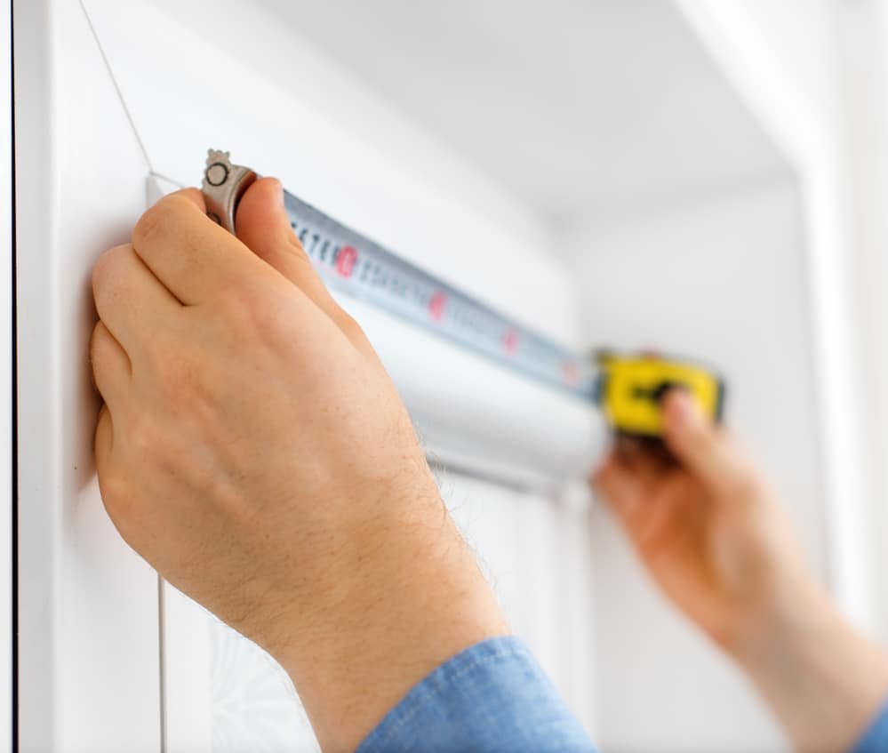 Man measuring the width of the window