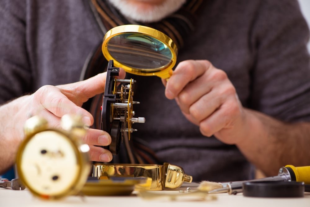 Old male watchmaker working in the workshop
