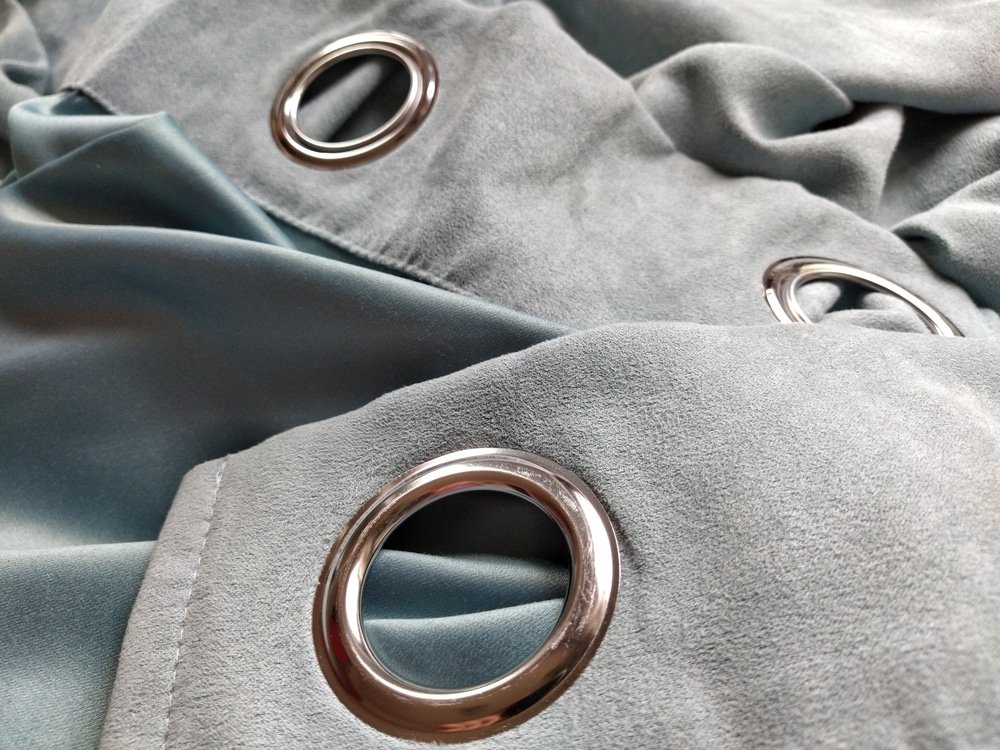 Two metal eyelets on gray-blue velvet curtains