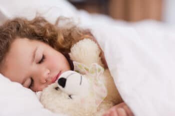 a little girl sleeping with her teddy