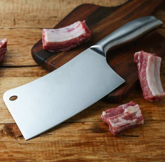 a cleaver knife and ribs on a wooden board