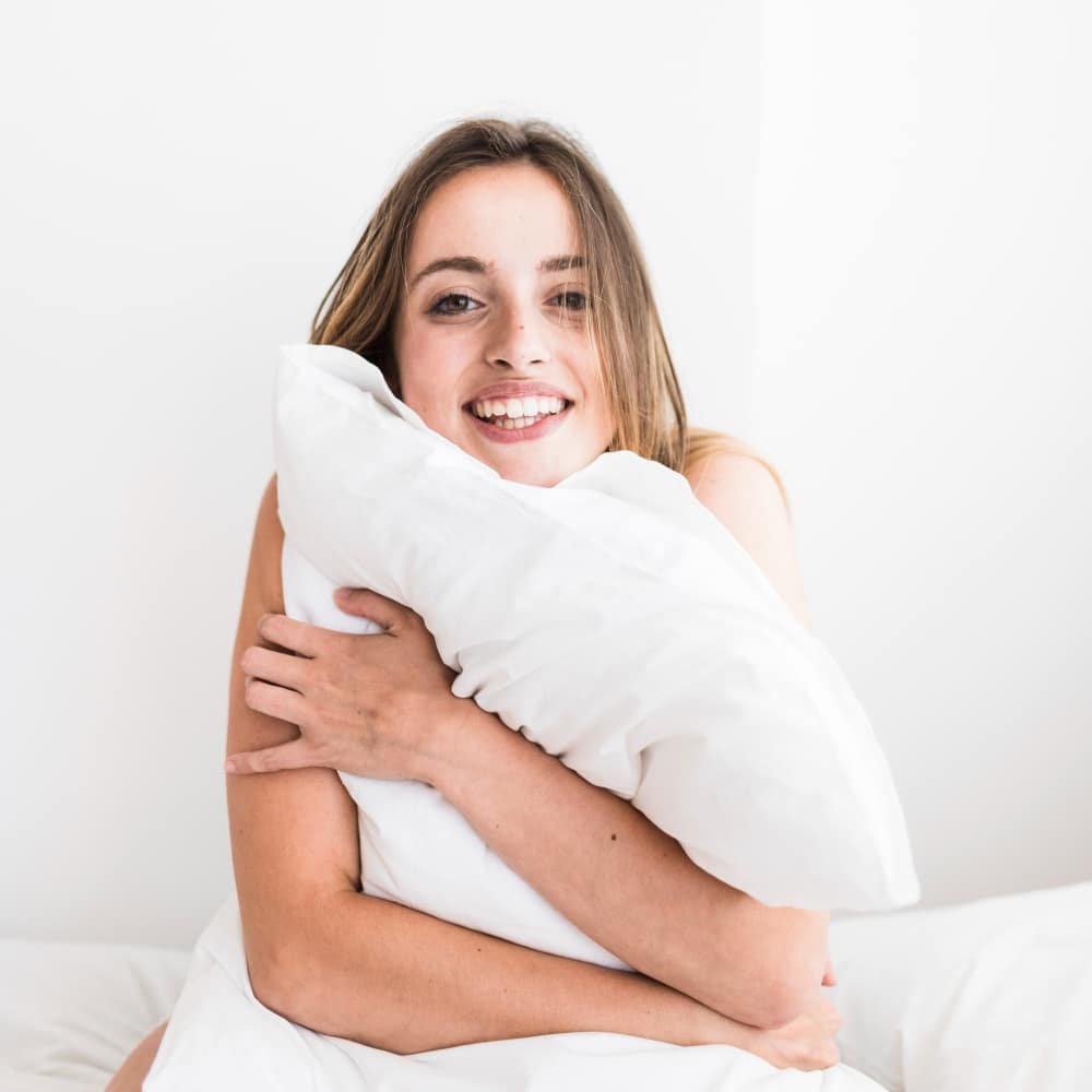 a happy woman hugging a pillow