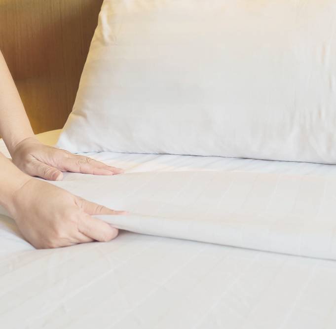 a lady setting up white bed sheet