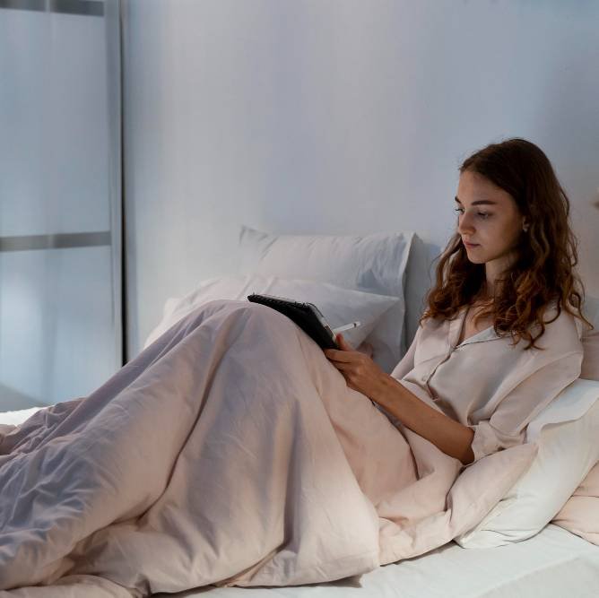 a lady using a gadget in bed