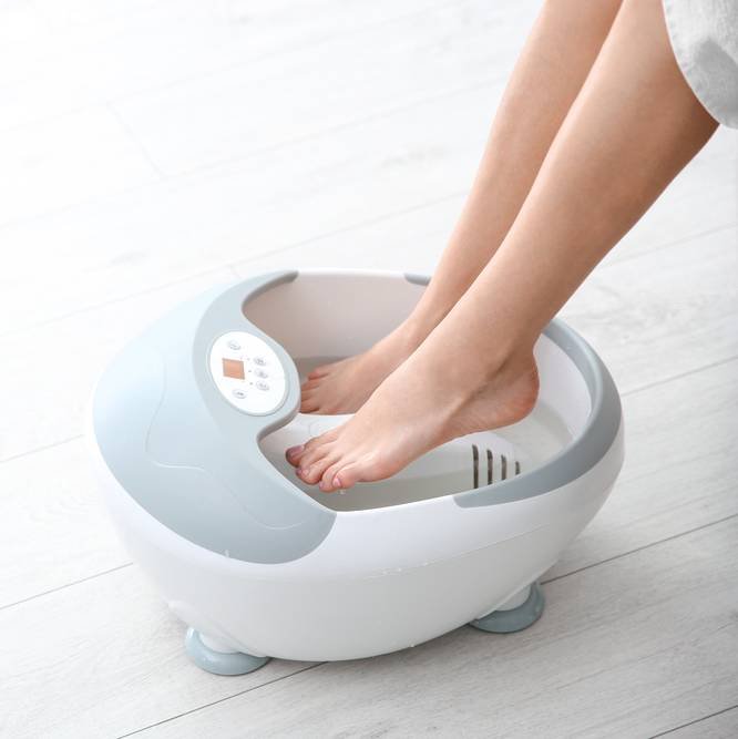 a lady with beautiful legs using an electric foot spa