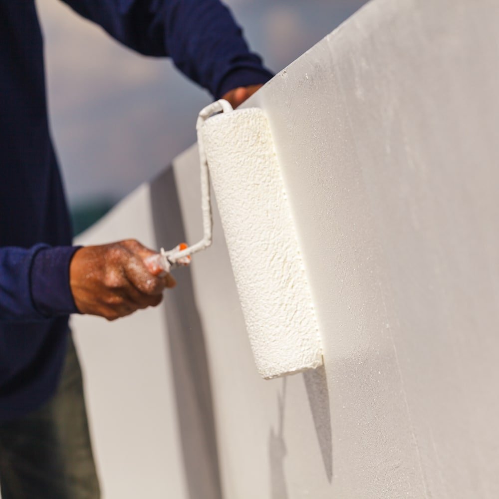 a man painting a wall using masonry paint