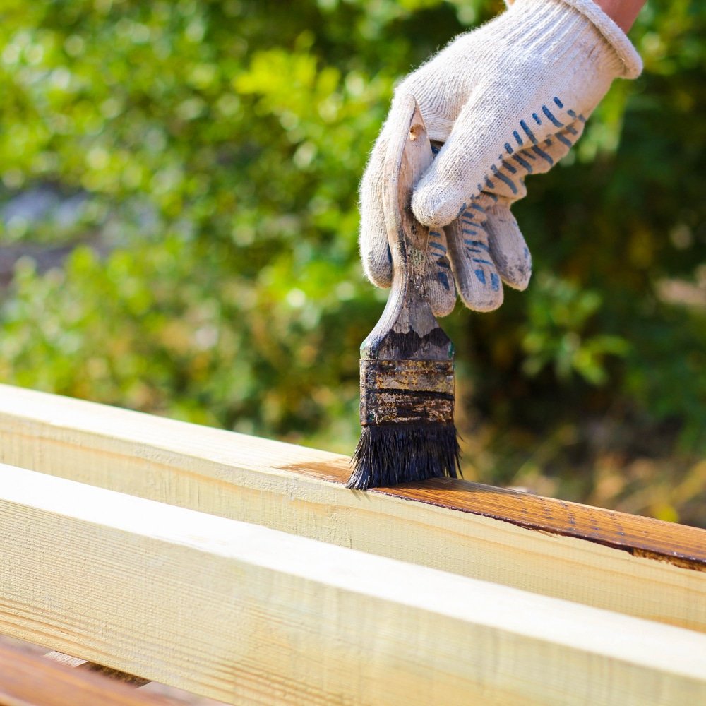 a man painting wood preserver
