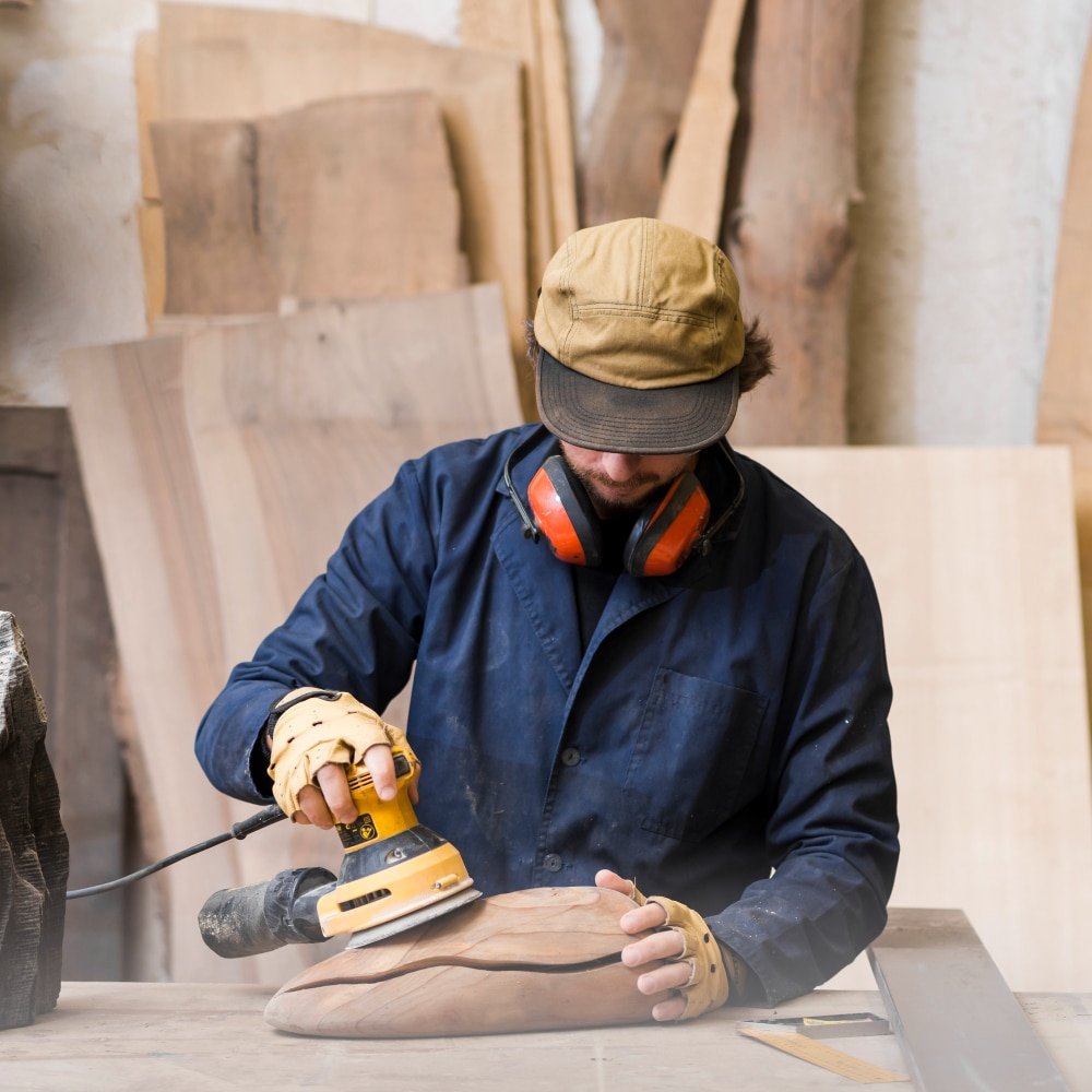 a man with ear defender around his neck using sander