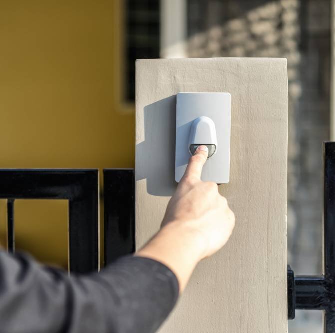 a man's hand pressing a doorbell button