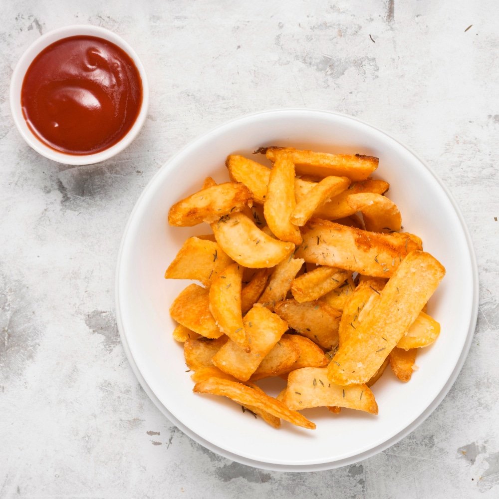 a portion of salted french fries on plate with ketchup