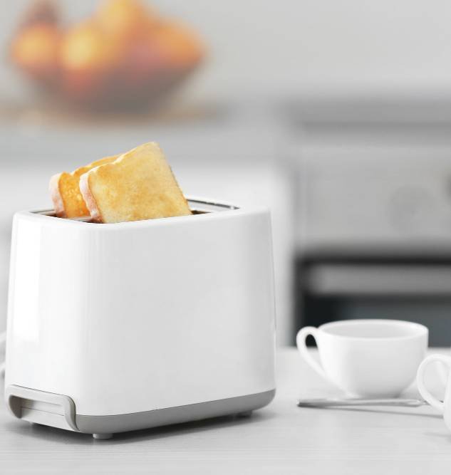 a toaster with dishes on a light kitchen table