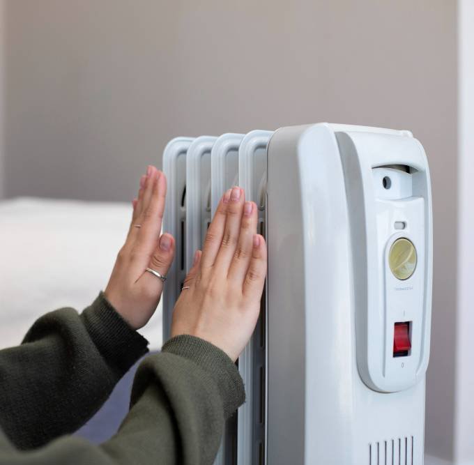 a woman getting warm near a heater