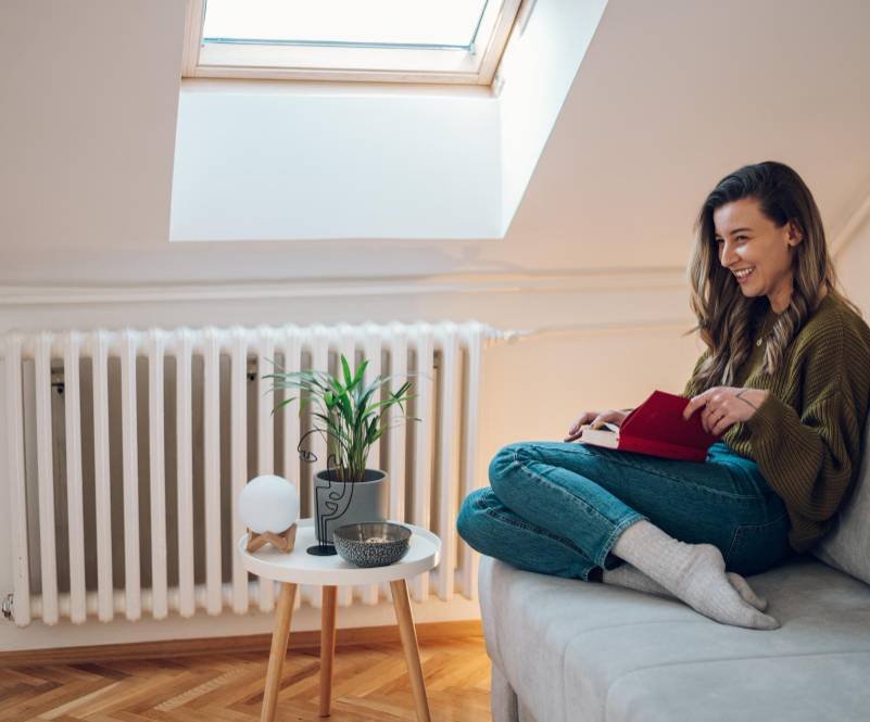 a woman reading a book near a heater