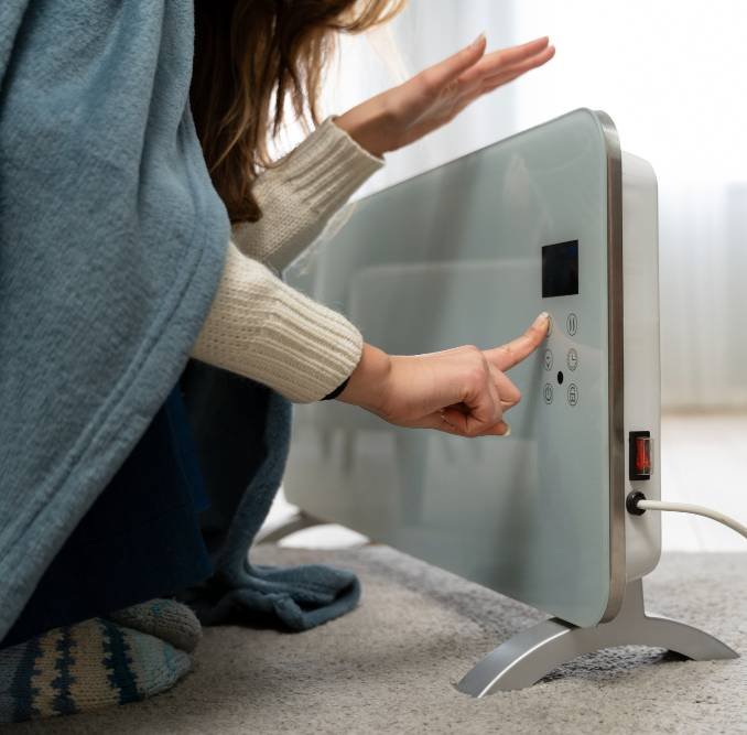 a woman sitting near a heater at home