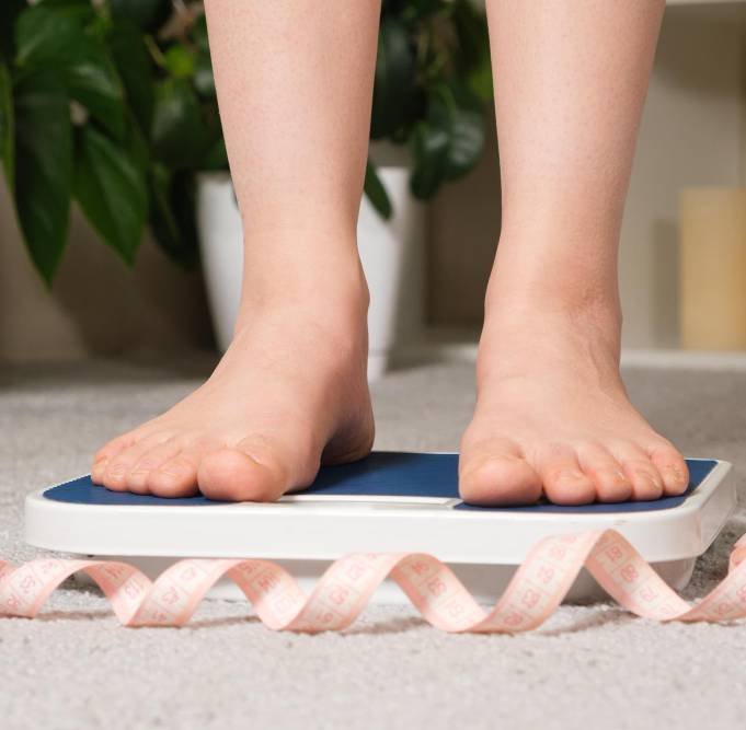 a woman using floor scales and measuring tape