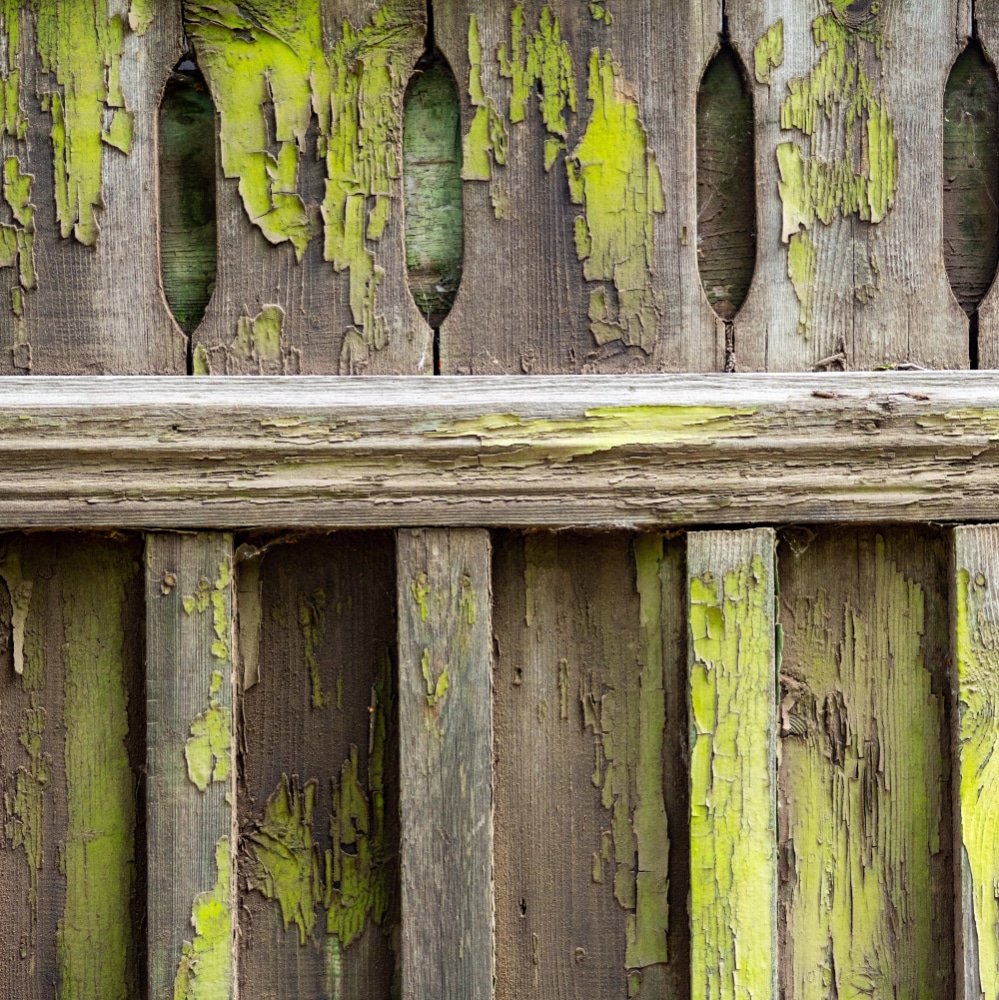 old wooden fence soiled with peeling green paint