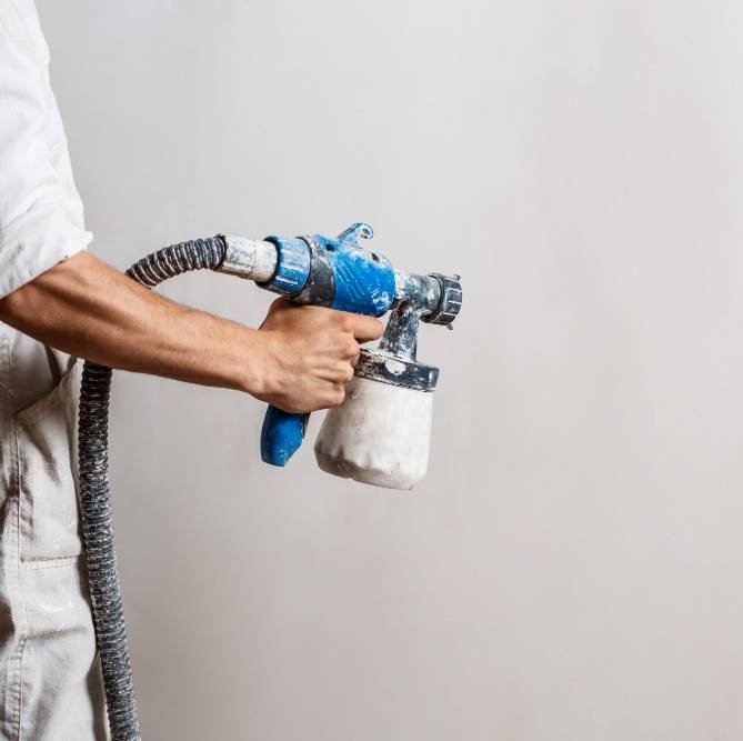 painting the wall with a white air sprayer